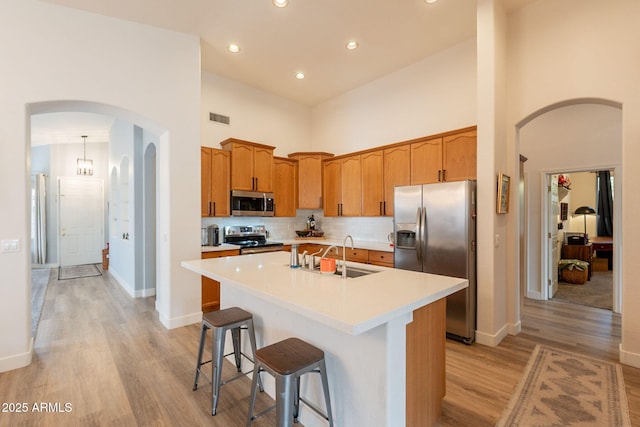 1635 E Harrison St, Chandler, AZ 85225 - kitchen featuring appliances with stainless steel finishes, arched walkways, a towering ceiling, light wood-style flooring, and light countertops