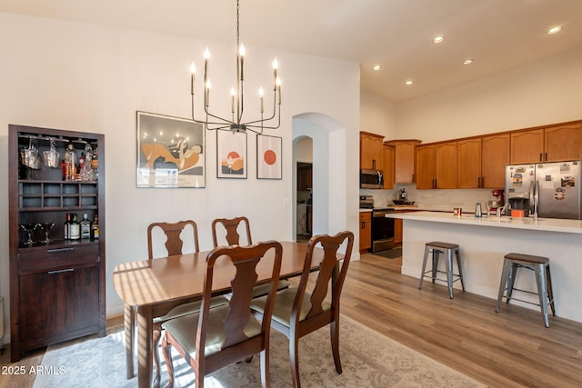 1635 E Harrison St, Chandler, AZ 85225 - dining area featuring arched walkways, light wood-style floors, recessed lighting, a chandelier, and a towering ceiling