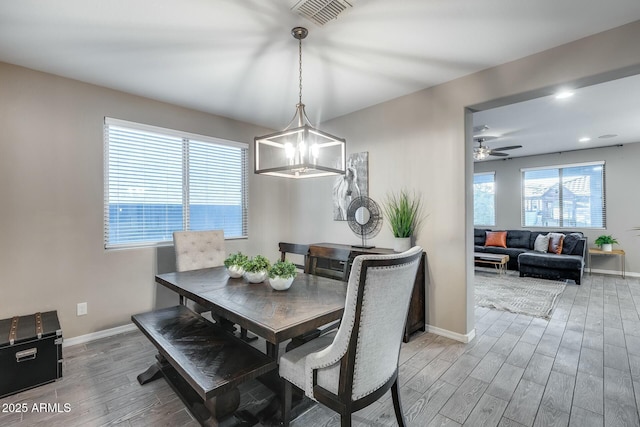 dining space featuring ceiling fan with notable chandelier and hardwood / wood-style flooring