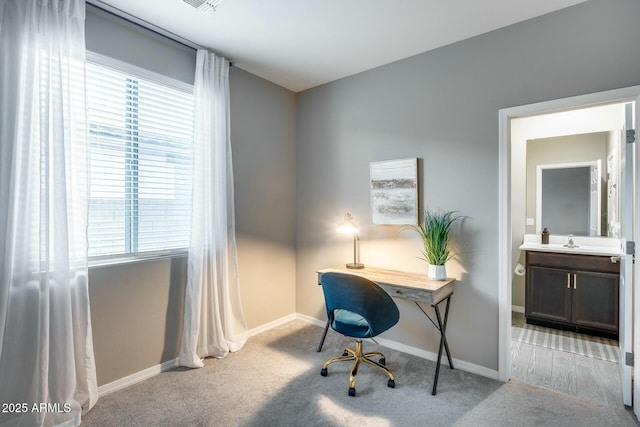 home office featuring light carpet, a wealth of natural light, and sink