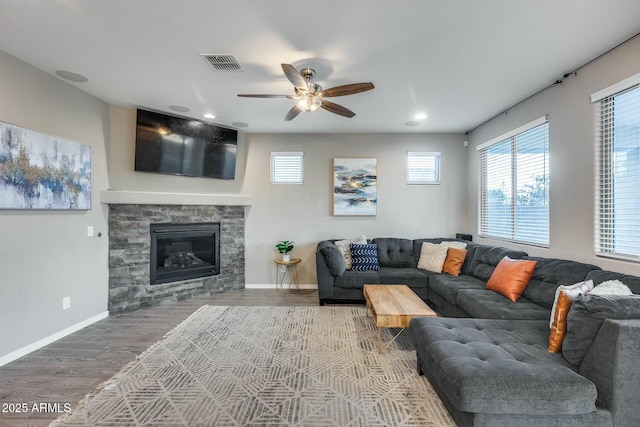 living room with hardwood / wood-style floors, ceiling fan, and a stone fireplace