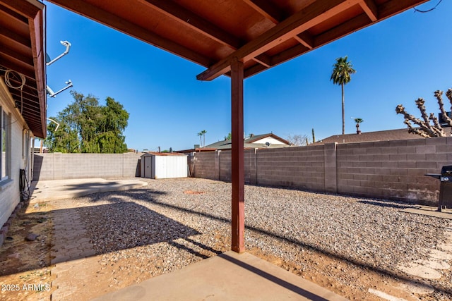 view of yard with a patio, an outdoor structure, a fenced backyard, and a shed