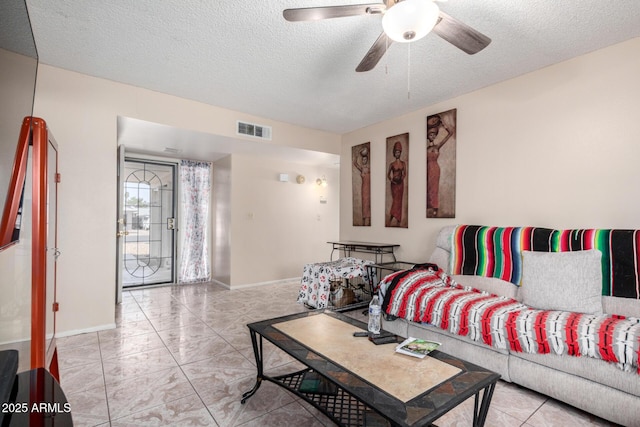 living room featuring baseboards, visible vents, a textured ceiling, and ceiling fan