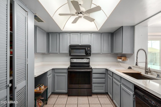 kitchen featuring visible vents, gray cabinetry, light tile patterned floors, black appliances, and a sink