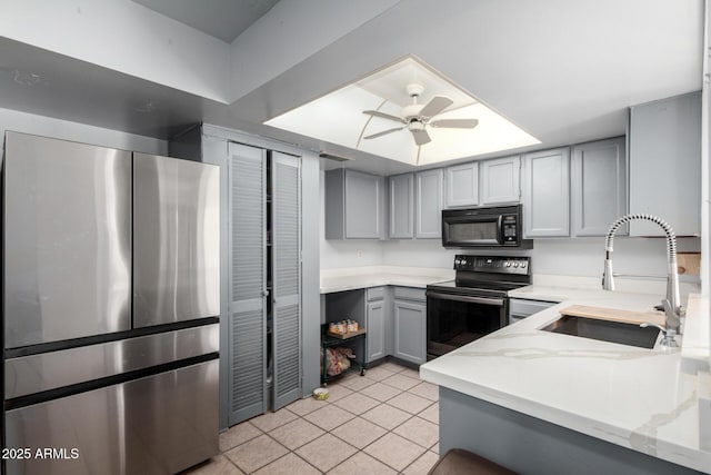 kitchen featuring black appliances, a ceiling fan, gray cabinets, a sink, and light tile patterned floors