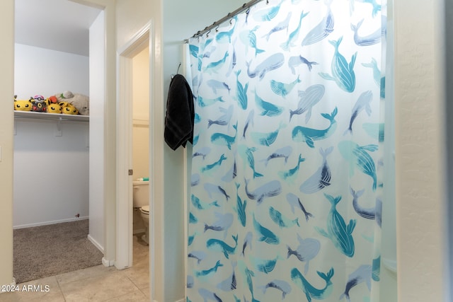 bathroom featuring toilet, a shower with curtain, and tile patterned floors