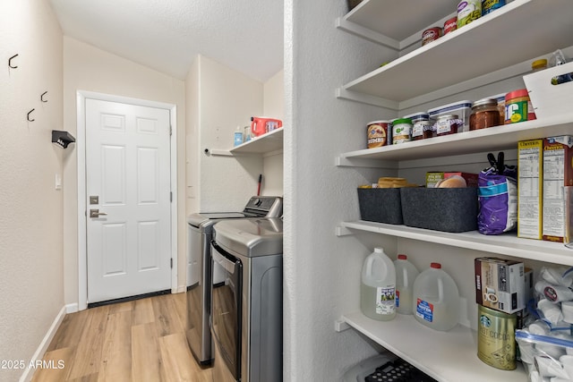 washroom featuring laundry area, light wood-style flooring, baseboards, and separate washer and dryer