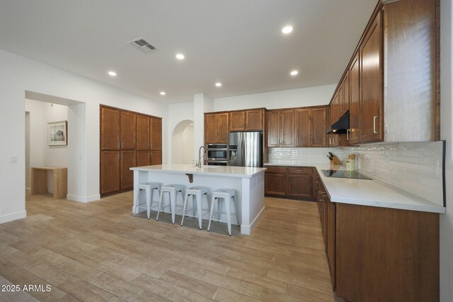 20834 W Prospector Way, Buckeye, AZ 85396 - kitchen with stainless steel appliances, under cabinet range hood, backsplash, light countertops, and a breakfast bar area