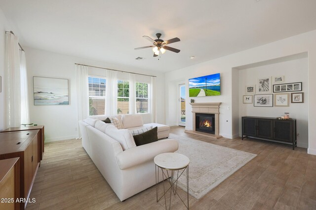 20834 W Prospector Way, Buckeye, AZ 85396 - living area featuring light wood-type flooring, ceiling fan, a glass covered fireplace, and baseboards