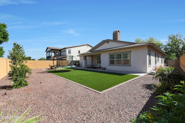 20834 W Prospector Way, Buckeye, AZ 85396 - rear view of house featuring a trampoline, stucco siding, a patio, and a chimney