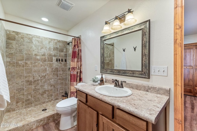 full bathroom with visible vents, toilet, vanity, and a tile shower