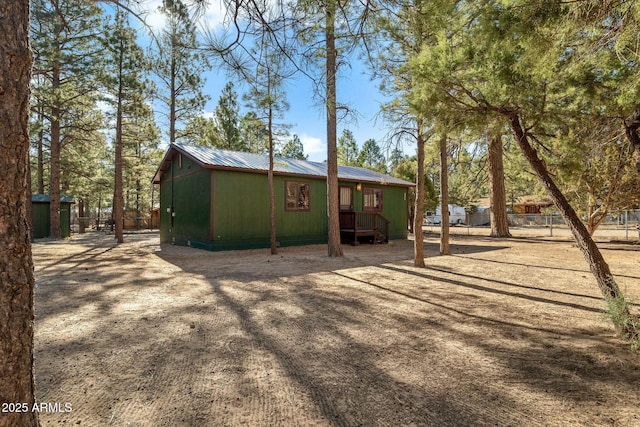 rear view of house featuring fence and metal roof