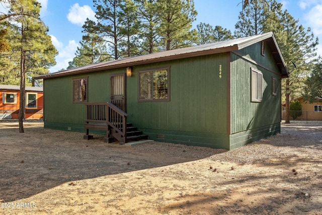 view of front facade featuring crawl space, metal roof, and dirt driveway