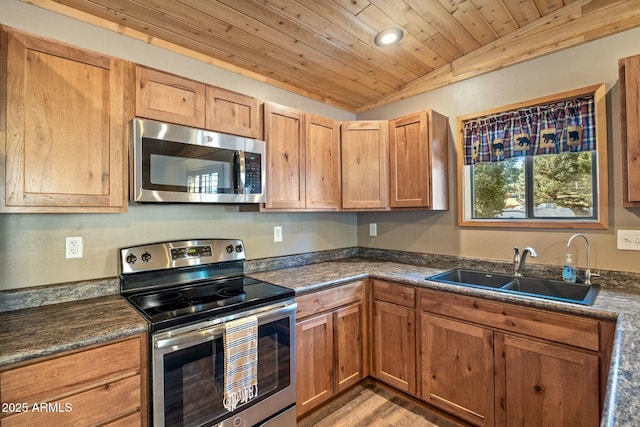 kitchen with dark countertops, wood ceiling, vaulted ceiling, appliances with stainless steel finishes, and a sink