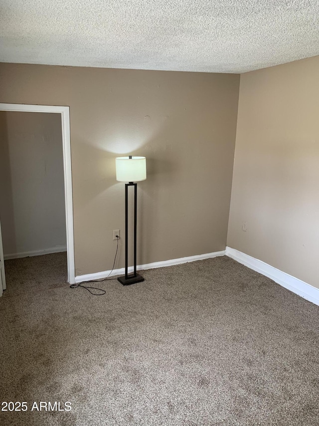 spare room with carpet floors, a textured ceiling, and baseboards