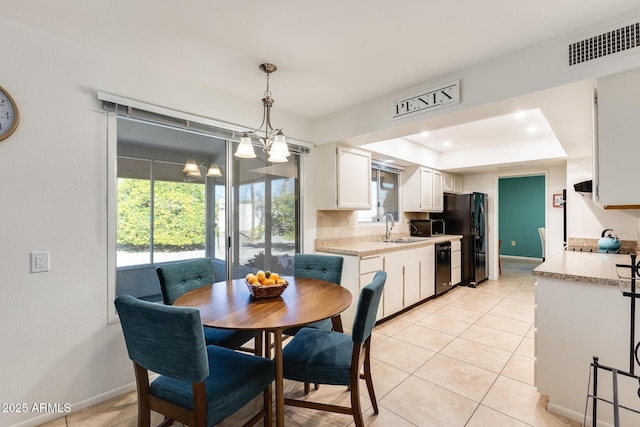 dining area featuring a raised ceiling, sink, an inviting chandelier, and light tile patterned flooring