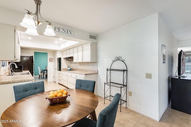 tiled dining area featuring a tray ceiling, sink, and an inviting chandelier