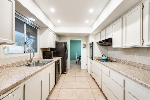 kitchen with light tile patterned floors, a raised ceiling, black appliances, white cabinets, and sink