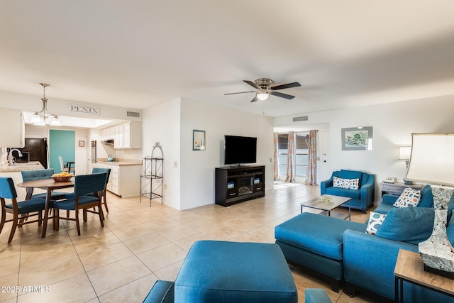 living room with ceiling fan with notable chandelier, sink, and light tile patterned floors