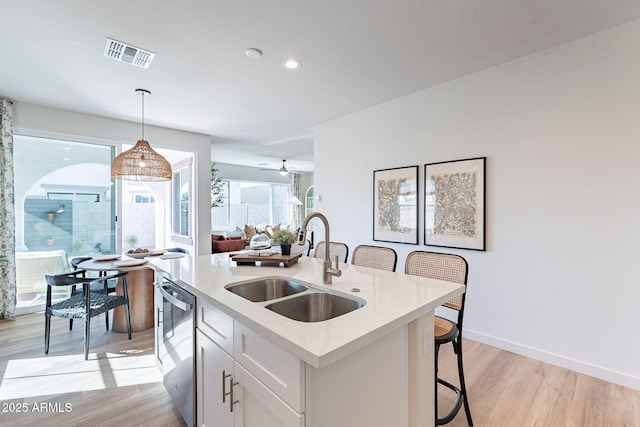 645 N Vine St, Chandler, AZ 85225 - kitchen featuring a sink, dishwasher, white cabinetry, hanging light fixtures, and light wood-style floors