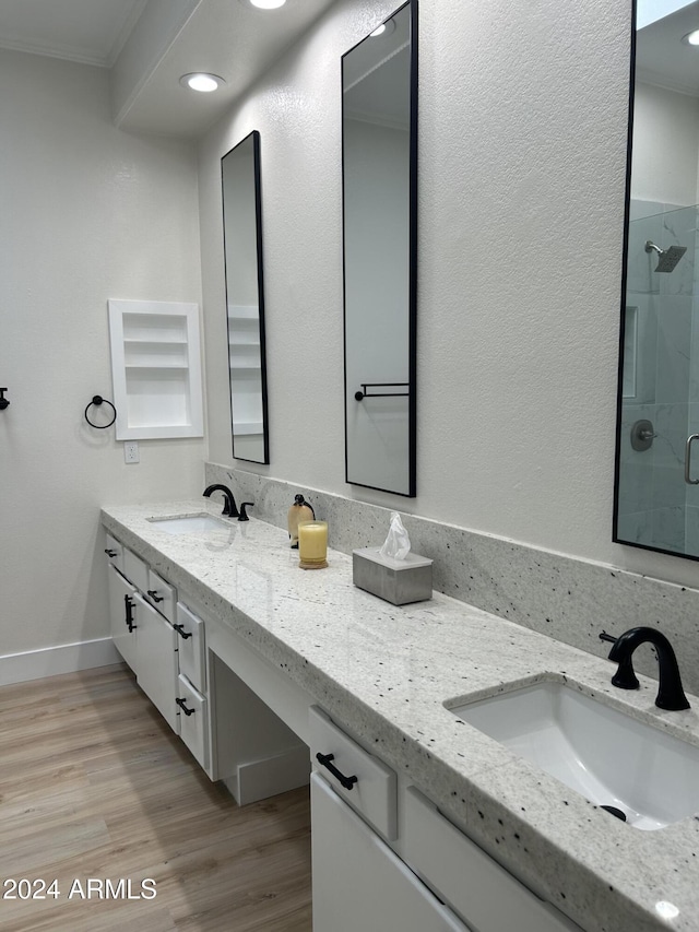 bathroom featuring vanity, hardwood / wood-style flooring, a shower with door, and crown molding