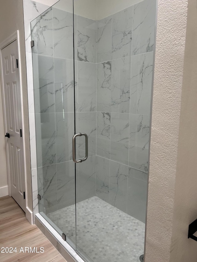 bathroom with wood-type flooring and an enclosed shower