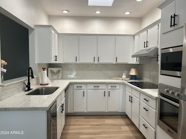 kitchen with white cabinets, sink, decorative backsplash, appliances with stainless steel finishes, and light stone counters