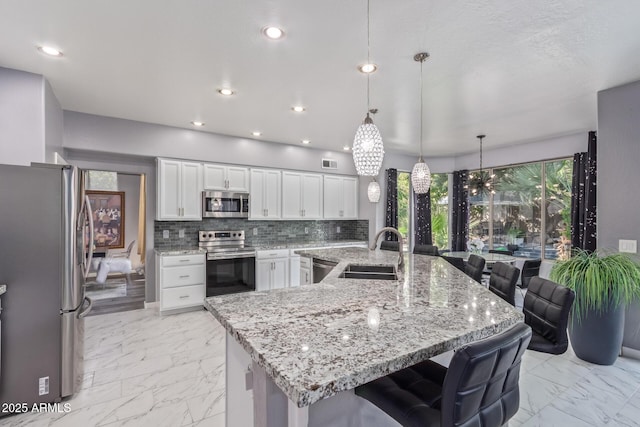 kitchen featuring a breakfast bar, stainless steel appliances, marble finish floor, backsplash, and a sink