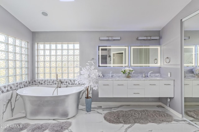 bathroom featuring double vanity, a soaking tub, marble finish floor, and a sink