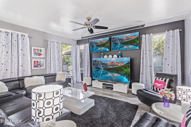 living area with a wealth of natural light, wood finished floors, and a ceiling fan