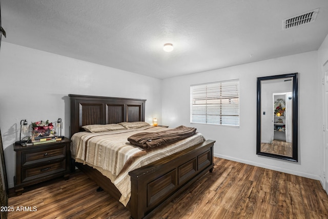 bedroom with dark hardwood / wood-style floors and a textured ceiling