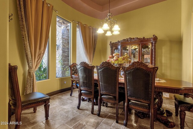 dining area with stone finish floor, a notable chandelier, and baseboards