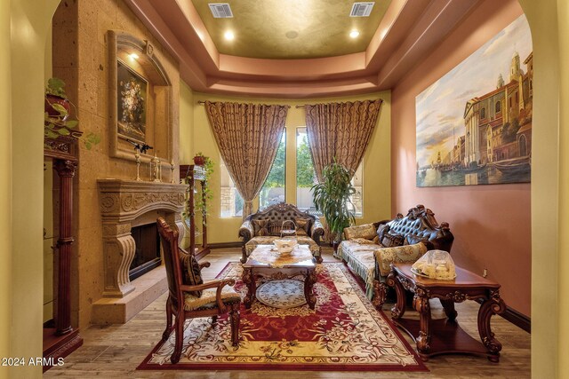 living area with a fireplace, wood finished floors, visible vents, and baseboards