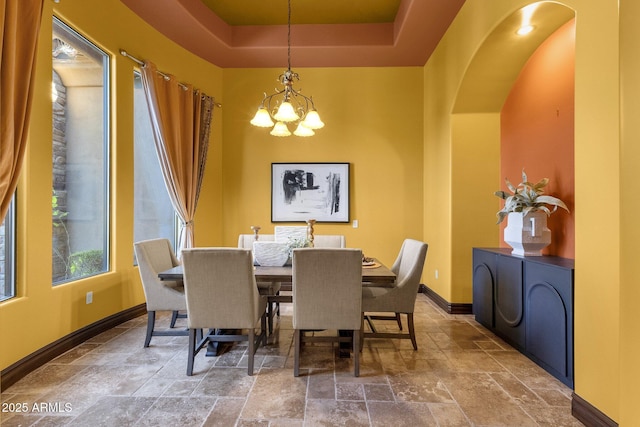 4301 E Taurus Pl, Chandler, AZ 85249 - dining area with stone tile floors, a chandelier, a tray ceiling, and arched walkways