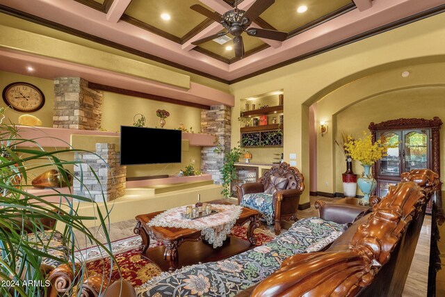 living room with arched walkways, coffered ceiling, a ceiling fan, ornamental molding, and beam ceiling