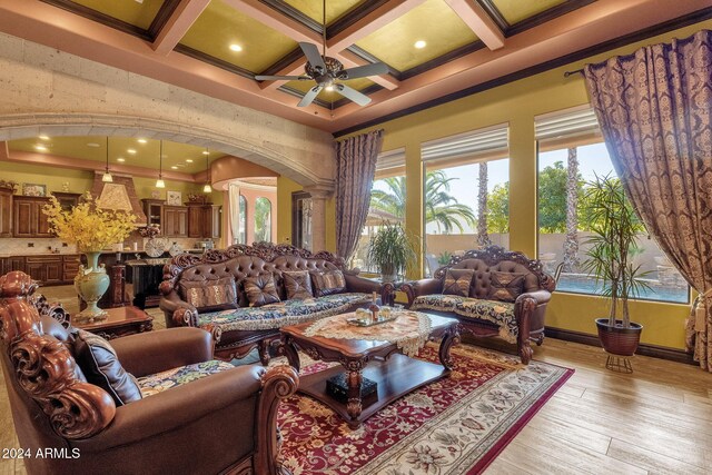 living room with arched walkways, coffered ceiling, a ceiling fan, a high ceiling, and light wood-type flooring