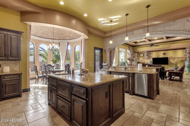 kitchen featuring open floor plan, an island with sink, a sink, and stone tile flooring