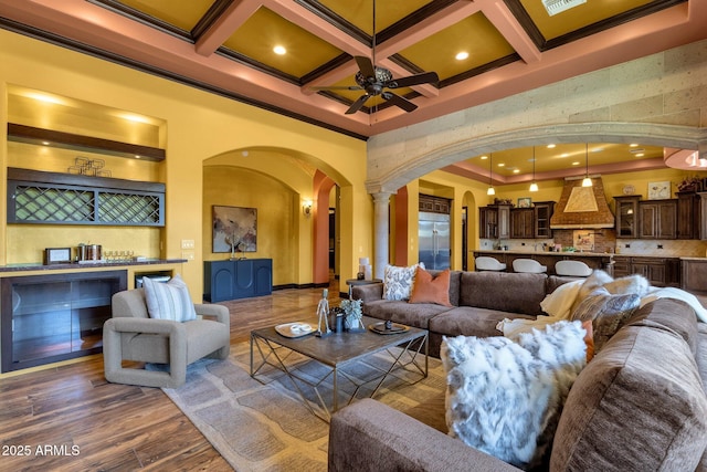 4301 E Taurus Pl, Chandler, AZ 85249 - living room featuring arched walkways, a ceiling fan, coffered ceiling, crown molding, and dark wood-style flooring