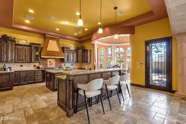 4301 E Taurus Pl, Chandler, AZ 85249 - kitchen featuring custom range hood, a center island, stone tile floors, a tray ceiling, and tasteful backsplash