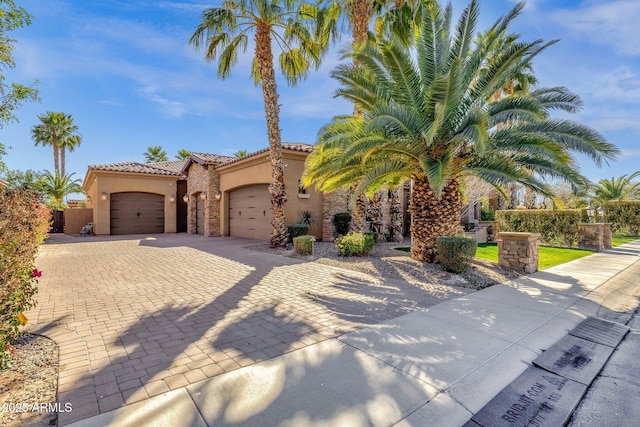 4301 E Taurus Pl, Chandler, AZ 85249 - mediterranean / spanish house with stucco siding, a garage, decorative driveway, a tiled roof, and stone siding