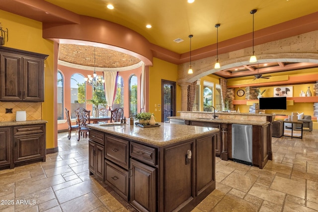 4301 E Taurus Pl, Chandler, AZ 85249 - kitchen with an island with sink, stone tile floors, arched walkways, recessed lighting, and plenty of natural light