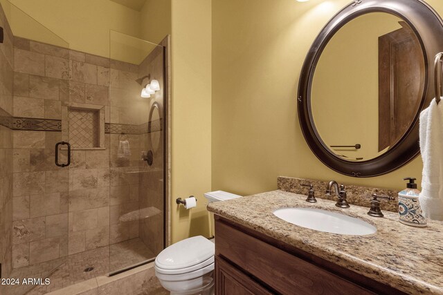 bathroom featuring a shower stall, toilet, and vanity