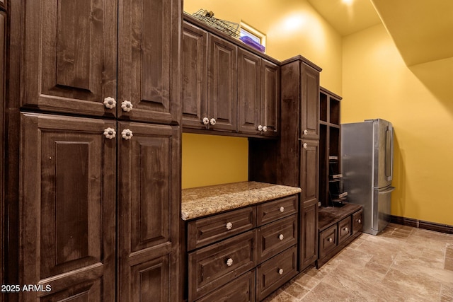 4301 E Taurus Pl, Chandler, AZ 85249 - kitchen with freestanding refrigerator, dark brown cabinetry, light stone counters, and light stone finish floors