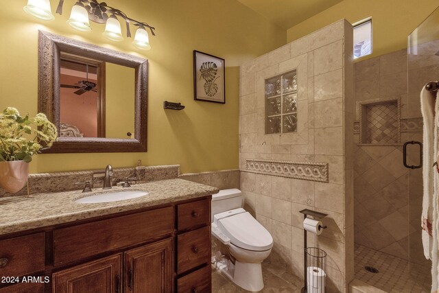 bathroom with toilet, a shower stall, tile walls, and vanity