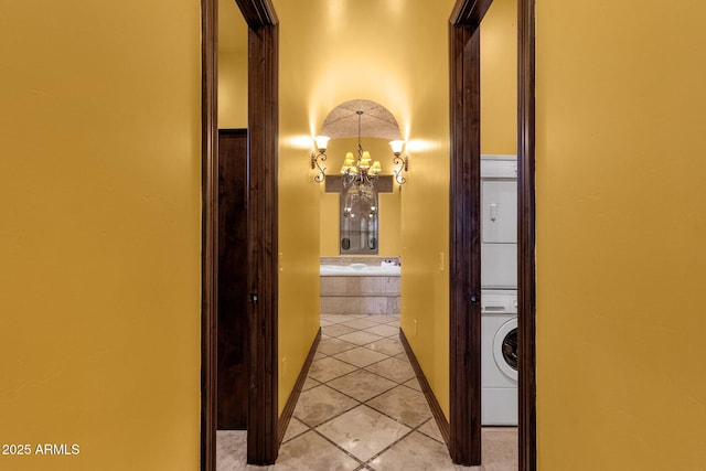 4301 E Taurus Pl, Chandler, AZ 85249 - corridor with stacked washer and clothes dryer, a chandelier, and light tile patterned floors