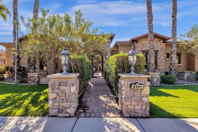 exterior space featuring stone siding, a front lawn, a tiled roof, and stucco siding