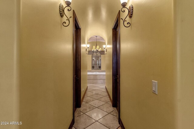 hall with light tile patterned floors and an inviting chandelier