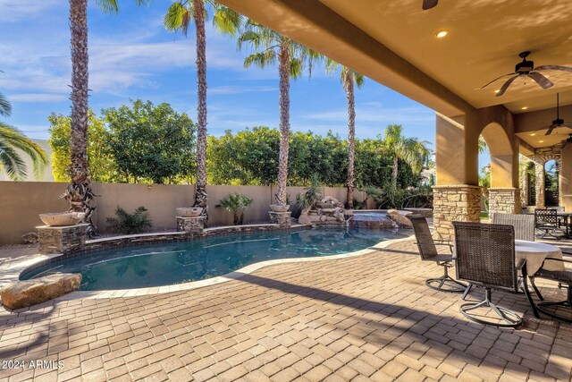 view of pool featuring a pool with connected hot tub, a patio area, a fenced backyard, and ceiling fan