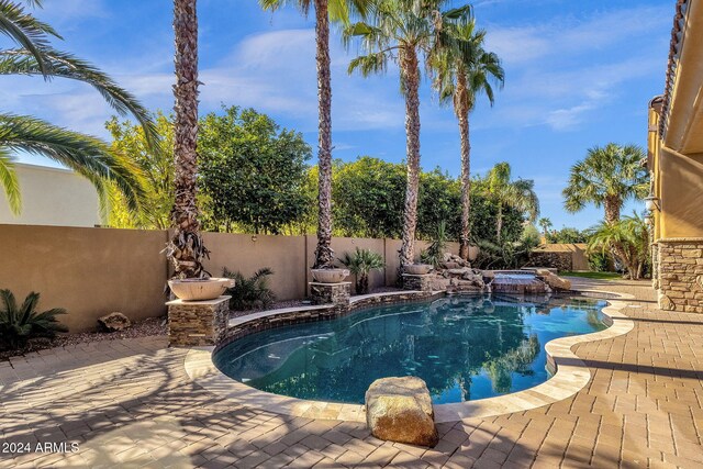 view of pool featuring a patio area, a fenced backyard, and a pool with connected hot tub