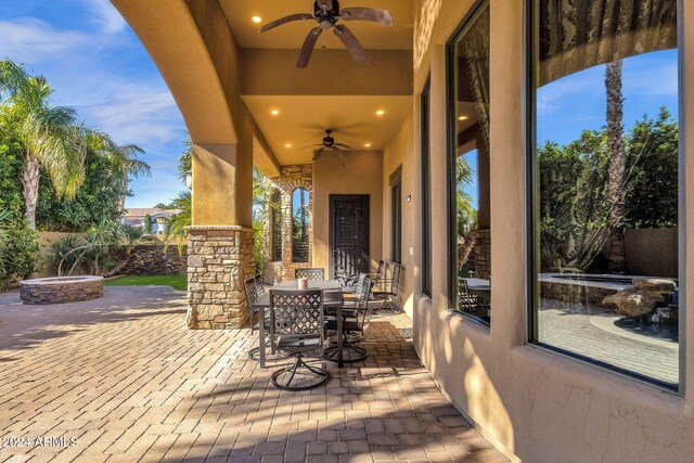 view of patio featuring ceiling fan, a fire pit, and outdoor dining space